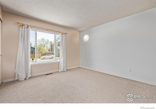 empty room featuring carpet floors, a textured ceiling, and baseboards