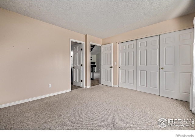 unfurnished bedroom with carpet, baseboards, a closet, and a textured ceiling