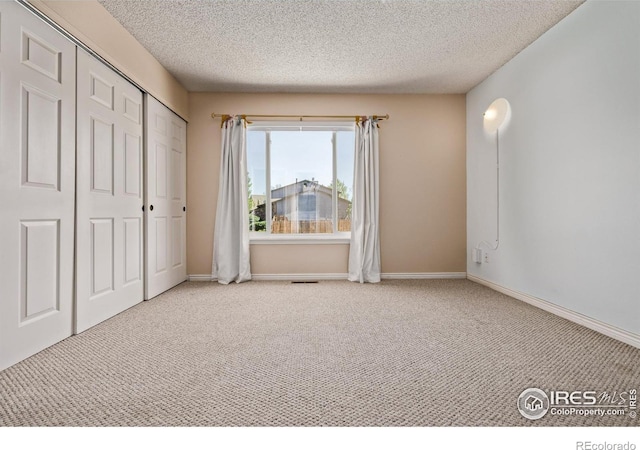 unfurnished bedroom featuring a textured ceiling, carpet floors, a closet, and baseboards