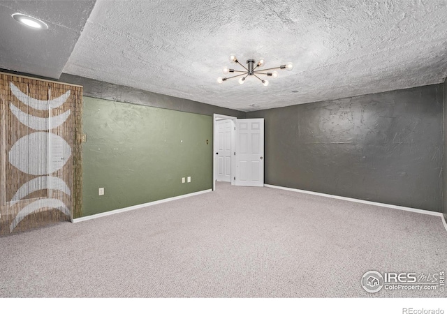 carpeted empty room featuring baseboards and a chandelier