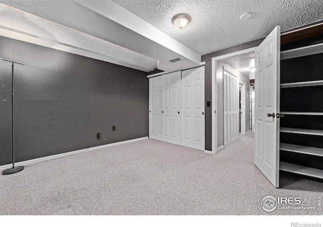 unfurnished bedroom with carpet, a textured ceiling, and baseboards