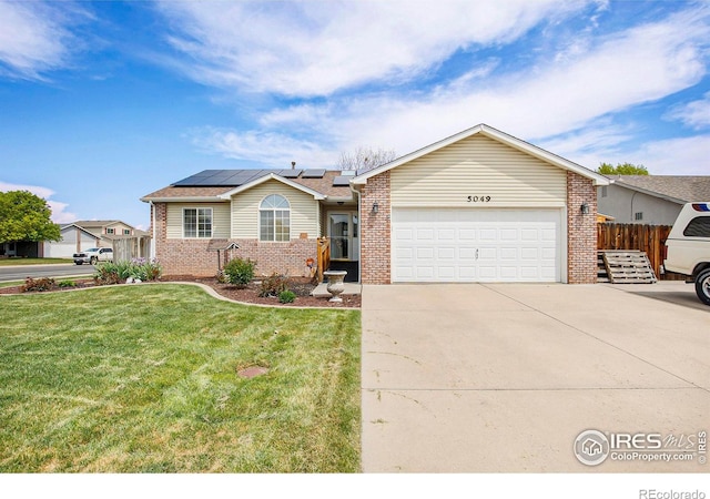 5049 W 2nd Street Rd, Greeley, CO 80634 - single story home with brick siding, an attached garage, roof mounted solar panels, and driveway