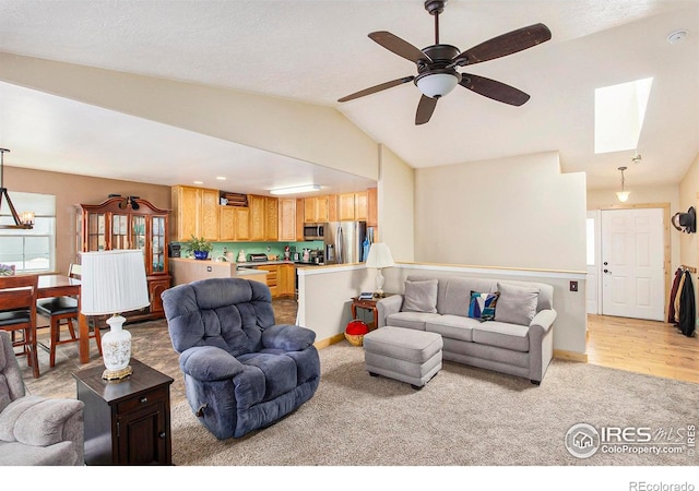 5049 W 2nd Street Rd, Greeley, CO 80634 - living area featuring light colored carpet, vaulted ceiling, ceiling fan, a skylight, and baseboards
