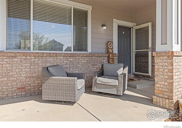 view of exterior entry with brick siding and a porch