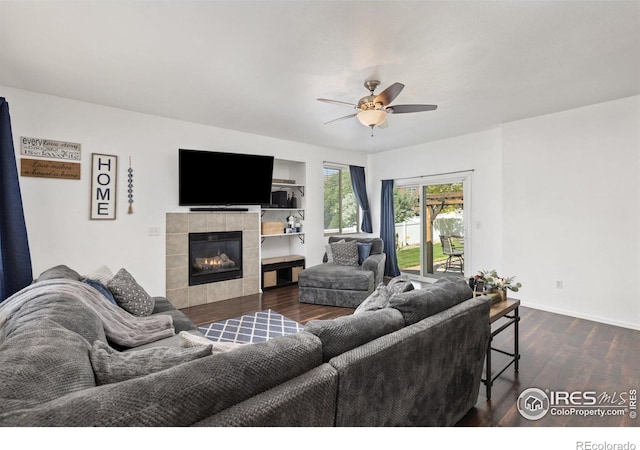 living area with ceiling fan, dark wood-type flooring, a fireplace, and baseboards