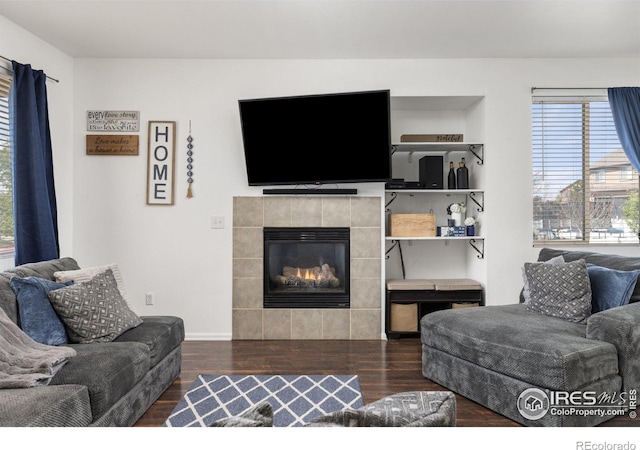 living room with wood finished floors and a tile fireplace