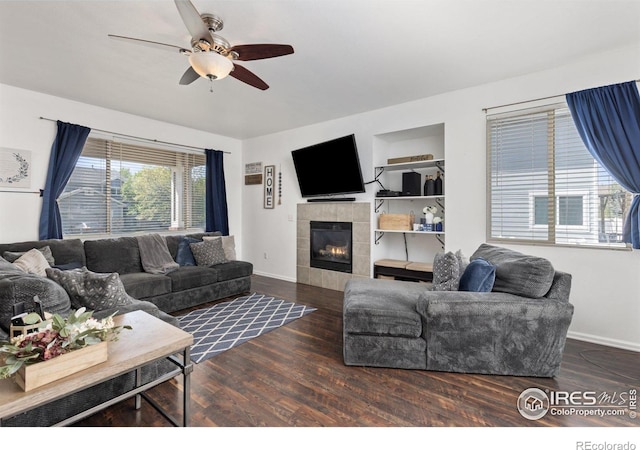 living room with wood finished floors, ceiling fan, a fireplace, and baseboards