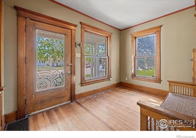 entryway featuring plenty of natural light, light wood-type flooring, crown molding, and baseboards