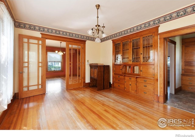 spare room with a chandelier, wood-type flooring, and french doors