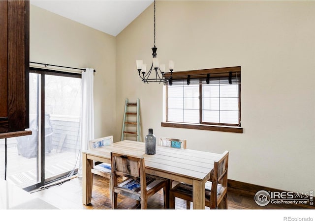 dining space with a chandelier, wood finished floors, lofted ceiling, and baseboards