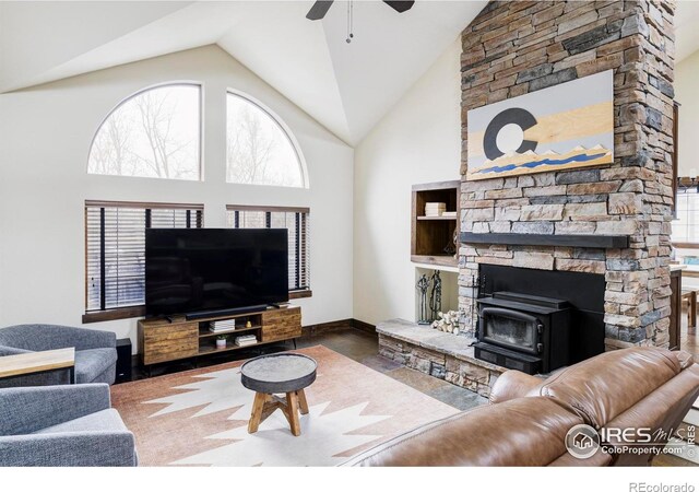 living room with ceiling fan, high vaulted ceiling, and a wood stove