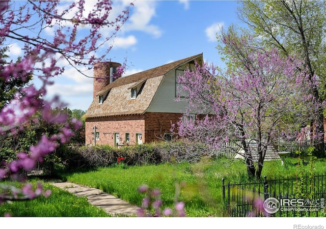 1341 N 95th St, Lafayette, CO 80026 - view of side of property featuring a chimney, fence, brick siding, and a gambrel roof