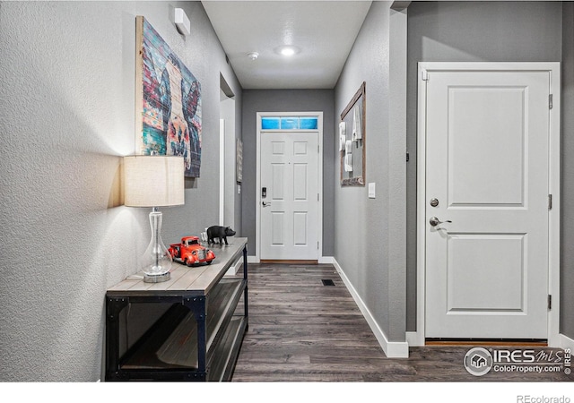 entryway with dark wood-style flooring, a textured wall, and baseboards