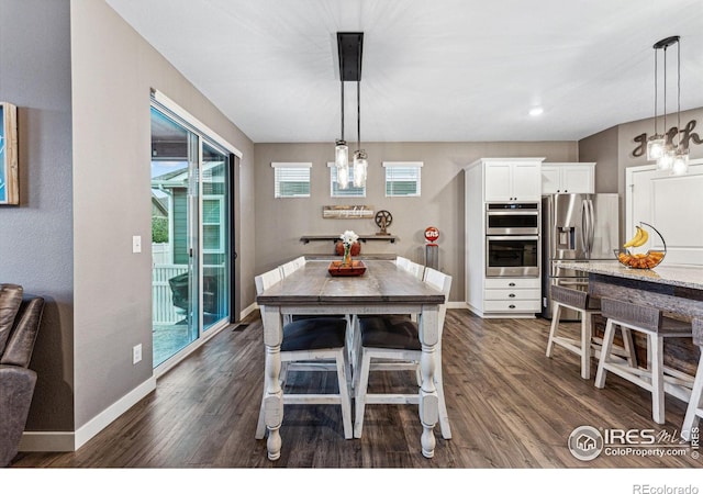 dining room with a chandelier, dark wood finished floors, and baseboards