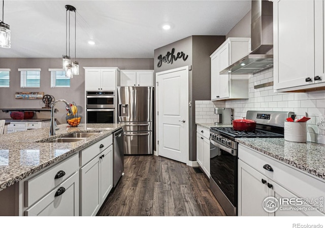 kitchen featuring appliances with stainless steel finishes, wall chimney exhaust hood, a sink, dark wood finished floors, and white cabinets