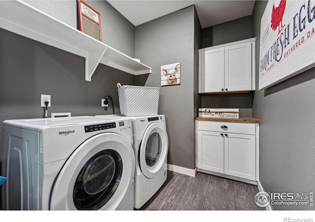 laundry area featuring washer and dryer, wood finished floors, baseboards, cabinet space, and a textured wall