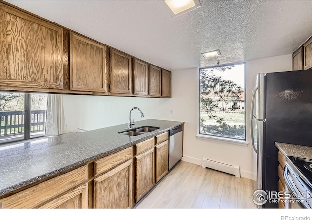 3363 Oneal Pkwy Unit 36, Boulder, CO 80301 - kitchen featuring a sink, a baseboard heating unit, stainless steel appliances, light wood-type flooring, and dark stone counters