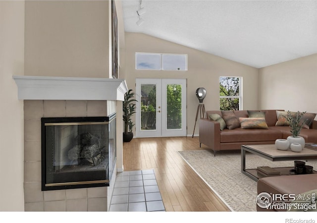 1606 Iris St, Broomfield, CO 80020 - living area with lofted ceiling, hardwood / wood-style flooring, a tile fireplace, and french doors
