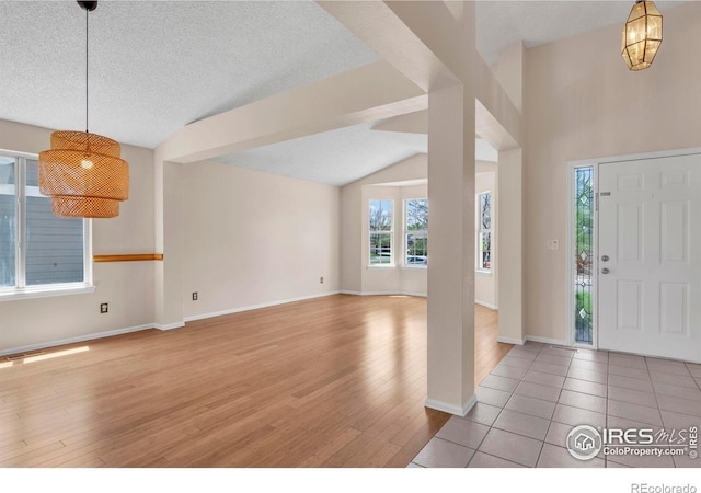 1606 Iris St, Broomfield, CO 80020 - foyer with light wood-style floors, lofted ceiling, a textured ceiling, and baseboards