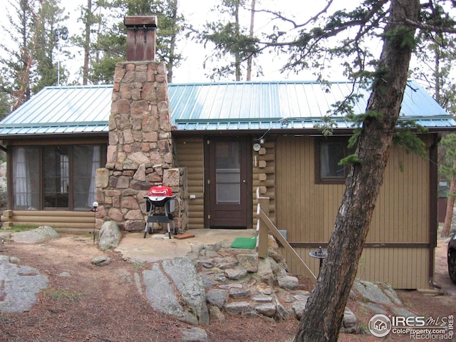 log home featuring a chimney, entry steps, metal roof, and log exterior