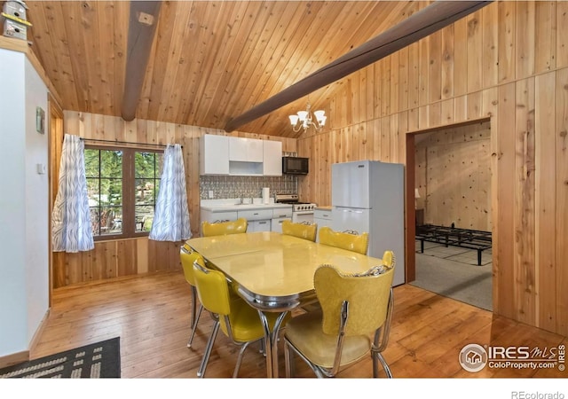 dining room with light wood finished floors, a chandelier, wood walls, and wooden ceiling