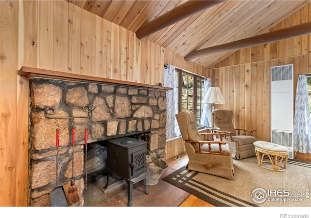 sitting room featuring a heating unit, wooden walls, a wood stove, and wood ceiling