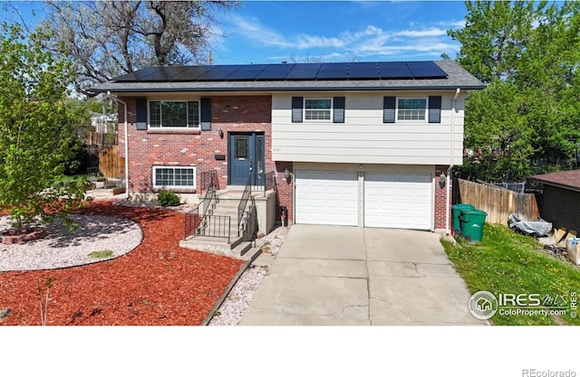 8351 Ralph Ln, Denver, CO 80221 - split foyer home with roof mounted solar panels, driveway, an attached garage, brick siding, and fence