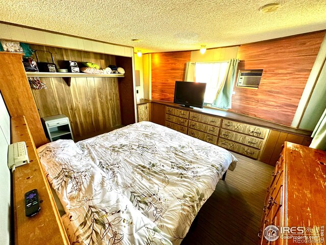 45908 County Road 39, Otis, CO 80743 - bedroom featuring wood walls, a textured ceiling, wood finished floors, and an AC wall unit