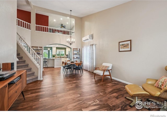 13106 Elizabeth St, Thornton, CO 80241 - living room featuring an AC wall unit, wood finished floors, baseboards, stairway, and a towering ceiling