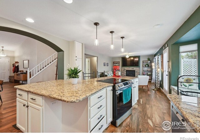 13106 Elizabeth St, Thornton, CO 80241 - kitchen with stainless steel electric range oven, open floor plan, white cabinets, a fireplace, and recessed lighting