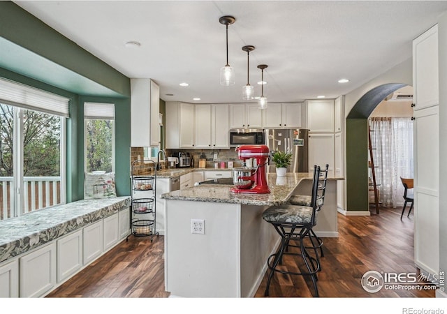 13106 Elizabeth St, Thornton, CO 80241 - kitchen featuring appliances with stainless steel finishes, arched walkways, a sink, dark wood-style flooring, and recessed lighting