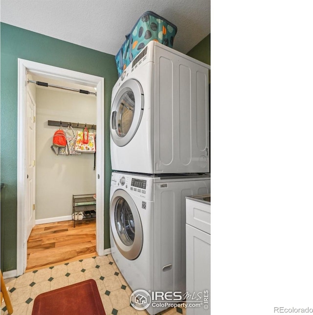 13106 Elizabeth St, Thornton, CO 80241 - laundry area featuring stacked washer / drying machine, cabinet space, baseboards, and light flooring