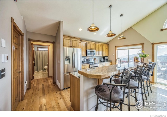 117 Mount Sherman Ct, Livermore, CO 80536 - kitchen with appliances with stainless steel finishes, light wood finished floors, tile countertops, a kitchen breakfast bar, and lofted ceiling