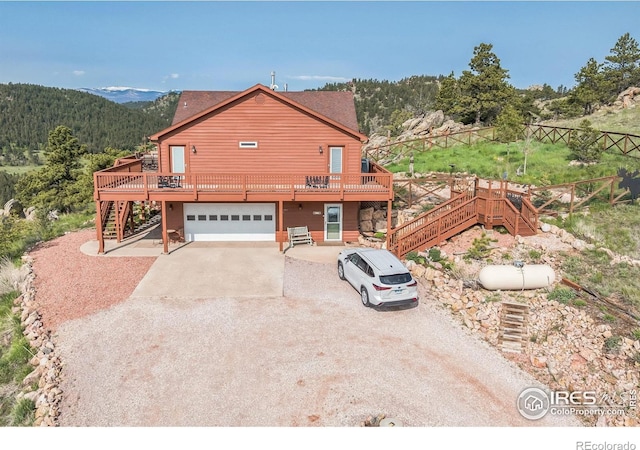 117 Mount Sherman Ct, Livermore, CO 80536 - view of front of property featuring stairway, gravel driveway, a deck, a garage, and a wooded view