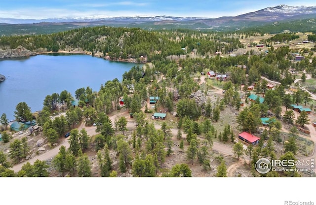 aerial view of property and surrounding area with a heavily wooded area and a water and mountain view