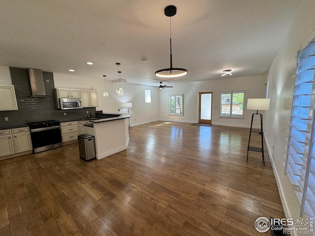 kitchen with stainless steel microwave, gas stove, open floor plan, dark wood finished floors, and recessed lighting