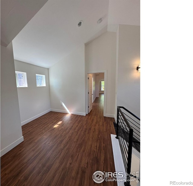 unfurnished living room with baseboards, dark wood-style flooring, and high vaulted ceiling