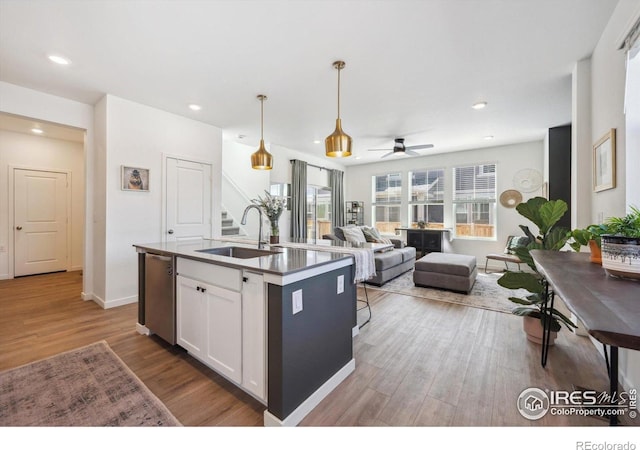 700 Lillibrook Pl, Erie, CO 80026 - kitchen with a sink, stainless steel dishwasher, wood finished floors, white cabinetry, and an island with sink