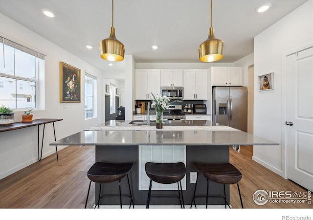 700 Lillibrook Pl, Erie, CO 80026 - kitchen with appliances with stainless steel finishes, a kitchen breakfast bar, white cabinetry, and recessed lighting
