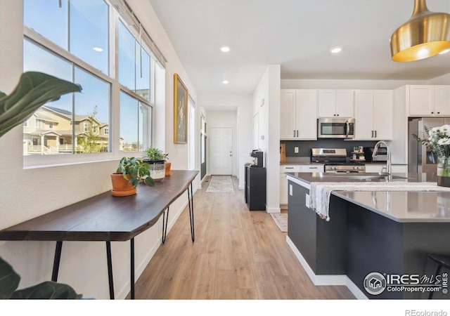 700 Lillibrook Pl, Erie, CO 80026 - kitchen featuring appliances with stainless steel finishes, light wood-style floors, white cabinets, hanging light fixtures, and a sink