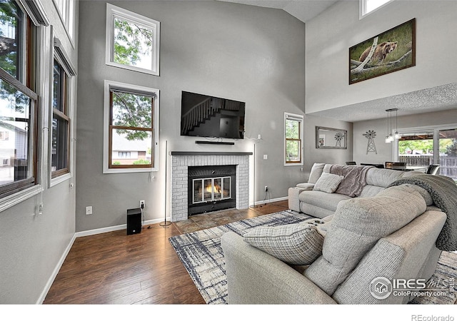 living area featuring a high ceiling, baseboards, healthy amount of natural light, and wood finished floors
