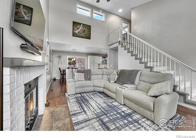 living area with a high ceiling, stairs, baseboards, a fireplace, and wood finished floors