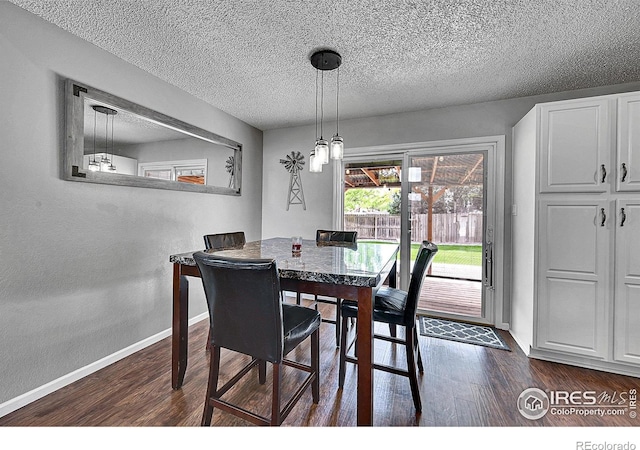 dining room featuring dark wood-style flooring, baseboards, and a textured ceiling