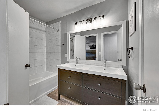 ensuite bathroom featuring wood finished floors, double vanity, and shower / bathtub combination