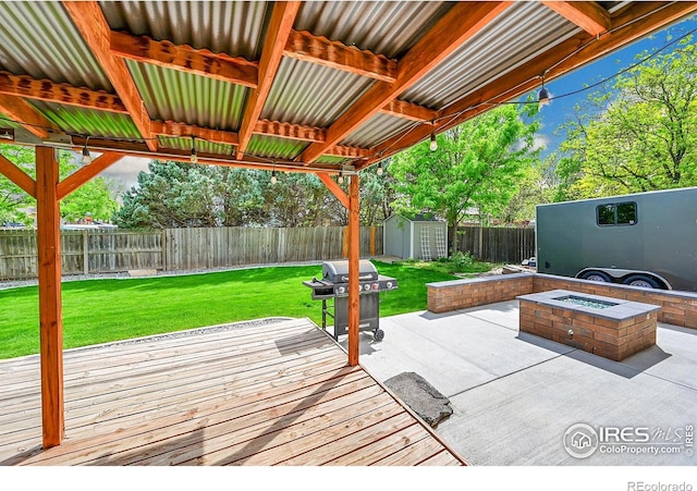 view of patio featuring area for grilling, a shed, a deck, an outdoor structure, and an outdoor fire pit