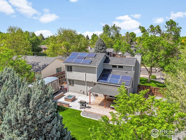 back of property featuring solar panels, a patio area, a chimney, a deck, and view of wooded area