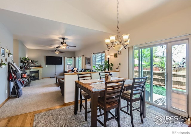 6601 Viburnum St, Wellington, CO 80549 - dining space with a chandelier, light wood-style flooring, a tiled fireplace, lofted ceiling, and baseboards