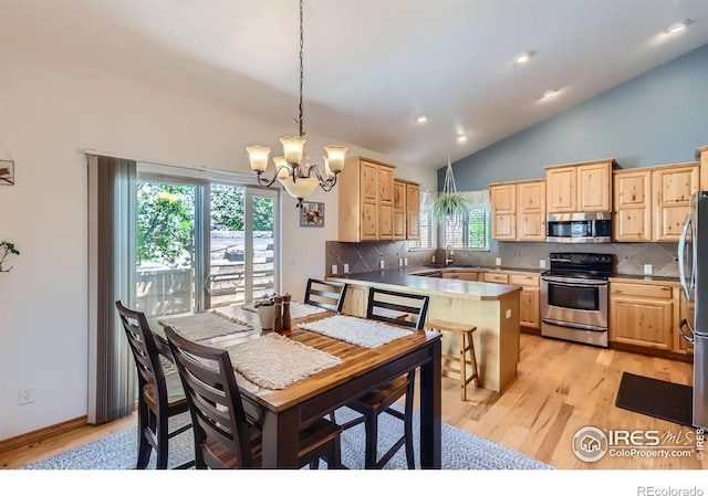 6601 Viburnum St, Wellington, CO 80549 - kitchen with stainless steel appliances, light brown cabinets, a chandelier, recessed lighting, and high vaulted ceiling