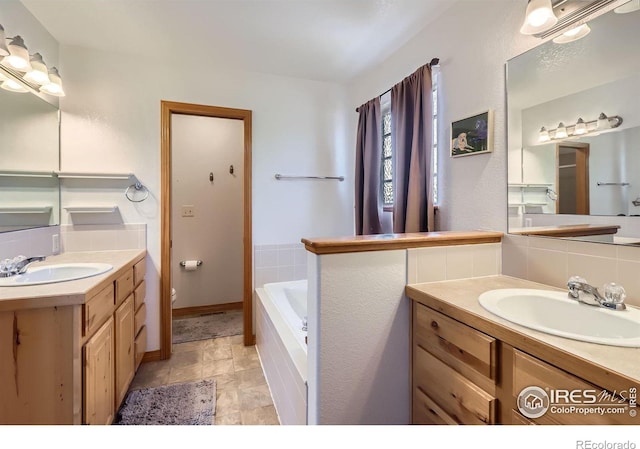 6601 Viburnum St, Wellington, CO 80549 - full bathroom with two vanities, a tub, toilet, baseboards, and decorative backsplash