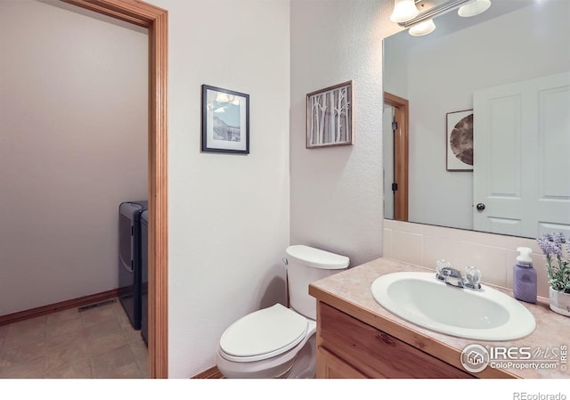 6601 Viburnum St, Wellington, CO 80549 - half bath featuring tasteful backsplash, toilet, vanity, and washer and dryer